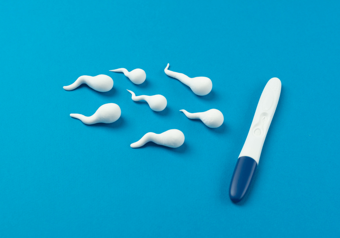 Pregnancy test and white sperm-shaped objects on a blue background.