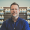 A man stands before shelves filled with various pill bottles